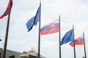 slovak european union flags together next to each other outdoors on a pole in a wind slovak and eu european union flags