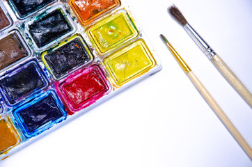 Palette with watercolors and brushes for paints on a white background. Watercolor paints. Brushes. Top and front view