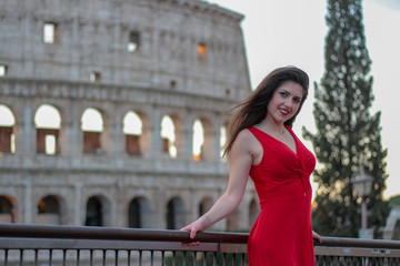 Pretty young girl in red dress in front of Colosseum, Rome, Italy. Rome symbol.