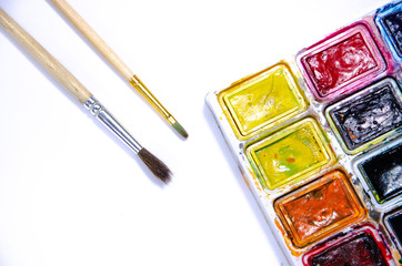 Palette with watercolors and brushes for paints on a white background. Watercolor paints. Brushes. Top and front view