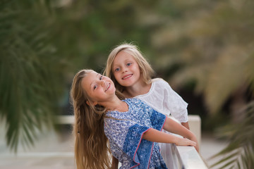 Two happy girls as friends hug each other in cheerful way. Little girlfriends in park. Children...