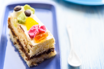 Cake with cream photographed close-up on a blue plate on a wooden background.