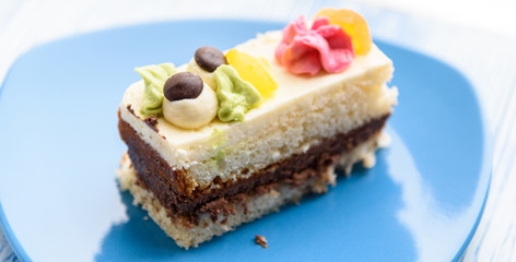 Cake with cream photographed close-up on a blue plate on a wooden background.