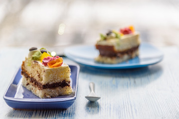 Cake with cream photographed close-up on a blue plate on a wooden background.