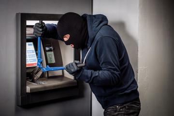 Thief with bolt cutter hacks an ATM. Law and crime concept
