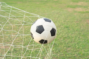 Soccer ball with net goal on green field