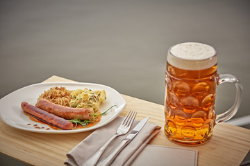sausages with potatoes and sauerkraut with a beer on the table overlooking the lake