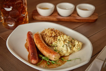 sausages with potatoes and sauerkraut with a beer on the table overlooking the lake