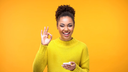 Beautiful african woman showing ok gesture, online shopping application, gadget