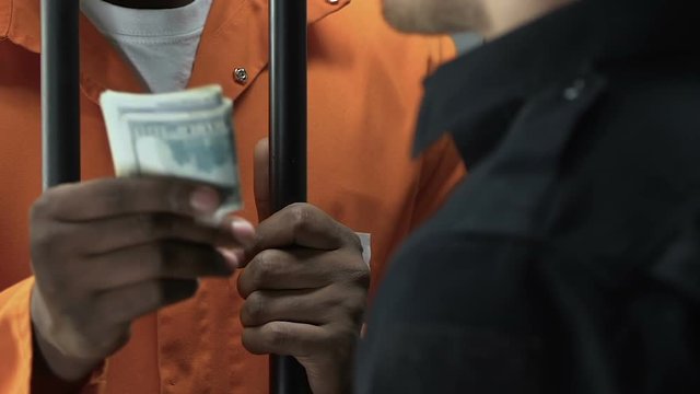 Afro-American criminal giving money as bribe to prison guard, breaking law