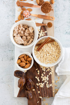 Ingredients for Brownie Balls with Oats, Raw Almonds, Cinnamon, Salt, Dates, and Cocoa on Cutting Board