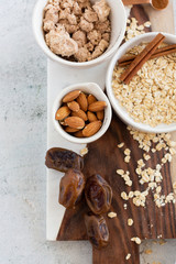 Ingredients for Brownie Balls with Oats, Raw Almonds, Cinnamon, Salt, Dates, and Cocoa on Cutting Board