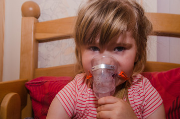 Little girl making inhalation with nebulizer at home. child asthma inhaler inhalation nebulizer...