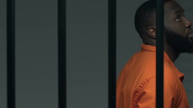 Depressed black prisoner walking in cell, waiting for death penalty, punishment