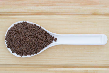 Flax seeds in a spoon on a wooden table.