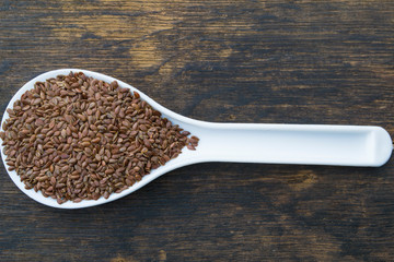 Flax seeds in a spoon on an old wooden table.