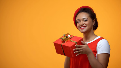 Good-looking female in red beret showing red gift box, holiday sale, celebration