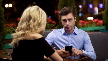Man looking with annoyance on girlfriend who stopping him surfing net, addiction