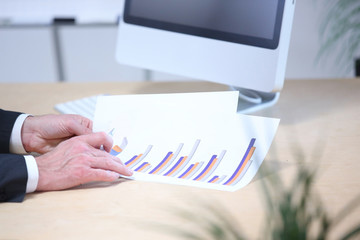 Hände halten ein Blatt Papier mit einer graphischen Analyse