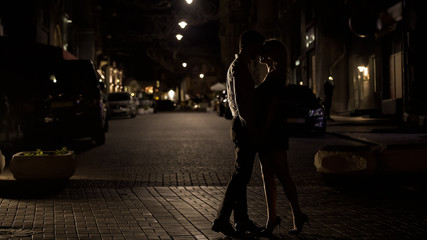 Loving couple kissing tenderly in night street, love in big city, sensuality