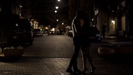 Two loving people kissing tenderly in night street, love in big city, dating