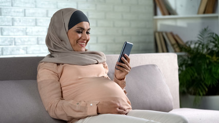 Happy muslim woman checking pregnancy examination online, healthcare, maternity