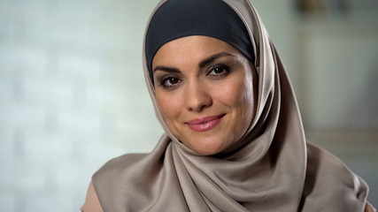 Modest muslim woman in hijab looking at camera with mysterious smile, closeup