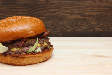 Fresh tasty homemade grilled burger with cheese and salad on wooden background with free space