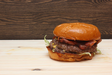 Fresh tasty homemade grilled burger with cheese and salad on wooden background with free space