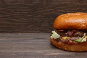 Fresh tasty homemade grilled burger with cheese and salad on wooden background with free space