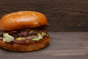 Fresh tasty homemade grilled burger with cheese and salad on wooden background with free space