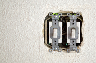 a double light switch with exposed wires in a wall with copy space
