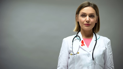 Caucasian female doctor with red ribbon, international HIV AIDS awareness sign