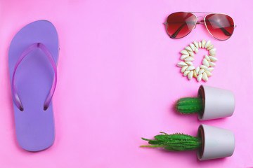 Beach purple flip flops, aviator sunglasses, seashell bracelet and succulent cacti cactus on a pink background. Summer colorful travel beach flat lay
