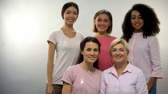 Group Of Women In Pink Shirts With Breast Cancer Ribbons Looking Into Camera