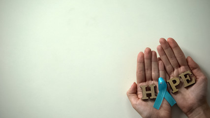 Blue ribbon in woman hands, prostate cancer awareness and prevention campaign