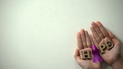 Purple ribbon in woman hands, epilepsy awareness and prevention campaign, care