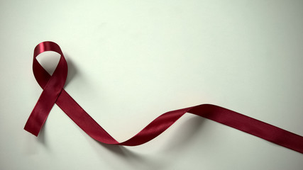 Burgundy ribbon in lady hands, multiple myeloma syndrome awareness, healthcare