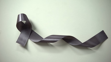 Lady putting gray ribbon on table, brain cancer awareness campaign, treatment