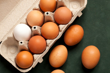 Close-up view of raw chicken eggs brown and white in box, egg white, egg brown on green background