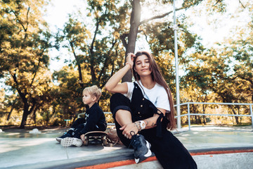 Beautiful young hipster mom and little son at the skatepark