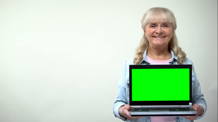 Aged lady showing laptop with green screen, online shopping discounts template