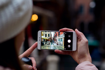 Young woman's hands holding smatphone and taking a travel photo.