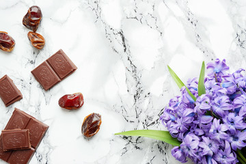 Black chocolate and dates on a marble background, top view
