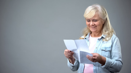 Aged retiree lady reading letter from children receiving good news loan approval