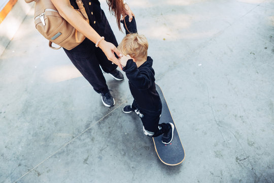 Young Mother Teaches Her Little Boy To Ride A Skateboard