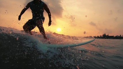 Surfer takes off with lots of splashes and rides the ocean wave at sunset. Weligama beach break in Sri Lanka