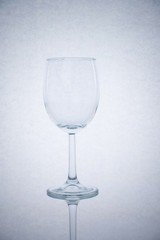 empty glass of wine on white background with reflection of legs