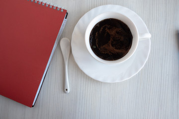 a notebook, and a cup of coffee on a white table