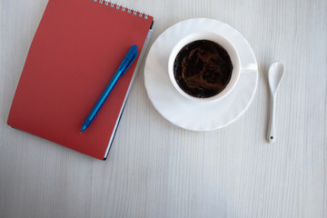 notebook, pen and cup of coffee on white table